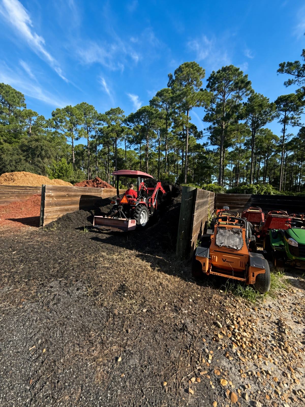 Mulch yard with fresh mulch piles and crew equipment